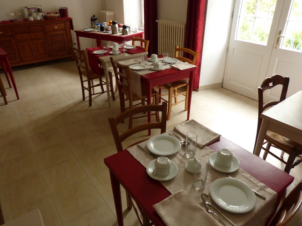Een eethoek met een rode tafel voor vier personen, omringd door houten stoelen.