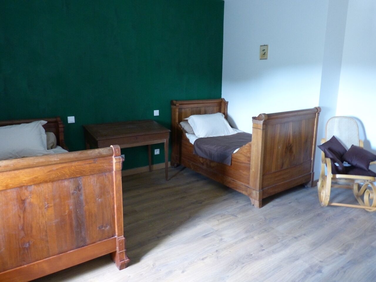 Ein Zimmer mit zwei Holzbetten, einem Holzstuhl und einem kleinen Tisch.