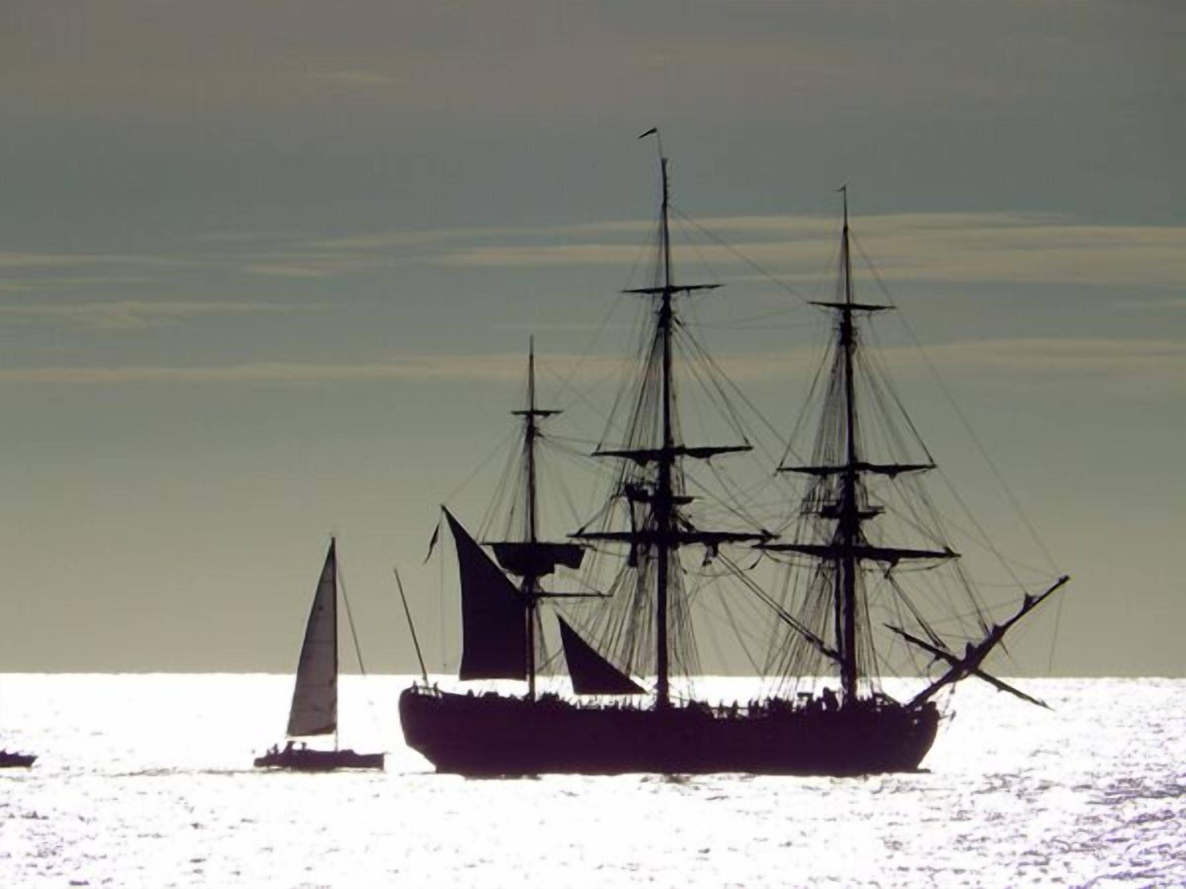 A large ship with multiple masts sailing on calm waters.