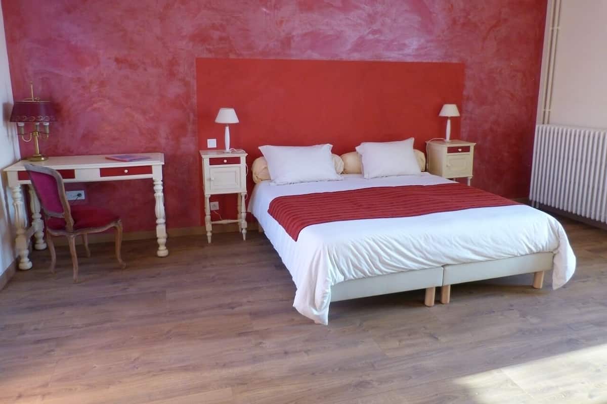 A bedroom with a bed, bedside tables, a desk, and a chair.