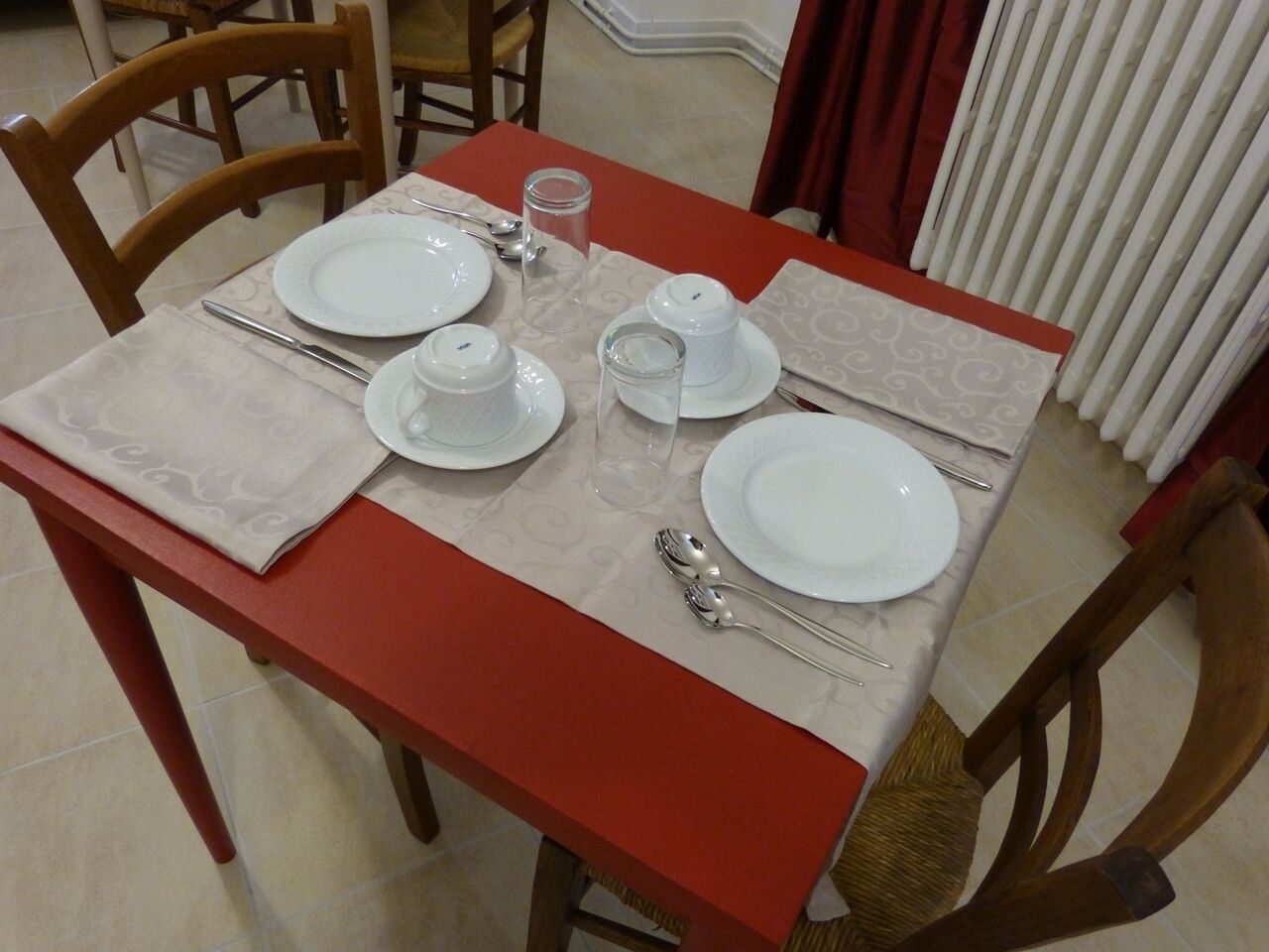 Uma mesa de jantar posta com pratos, talheres e um copo.