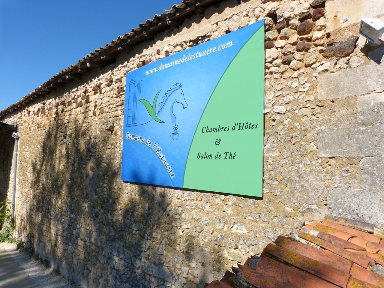 Un letrero en una pared de piedra con el texto 'Domaine de l'Estuaire' y 'Chambres d'Hôtes Salon de Thé'.