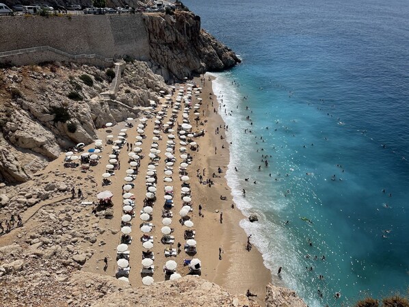 A beach with rows of umbrellas and people sunbathing.