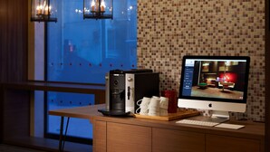 Une pièce moderne équipée d’une machine à café, d’un écran d’ordinateur et d’une tasse de café posée sur une table en bois.