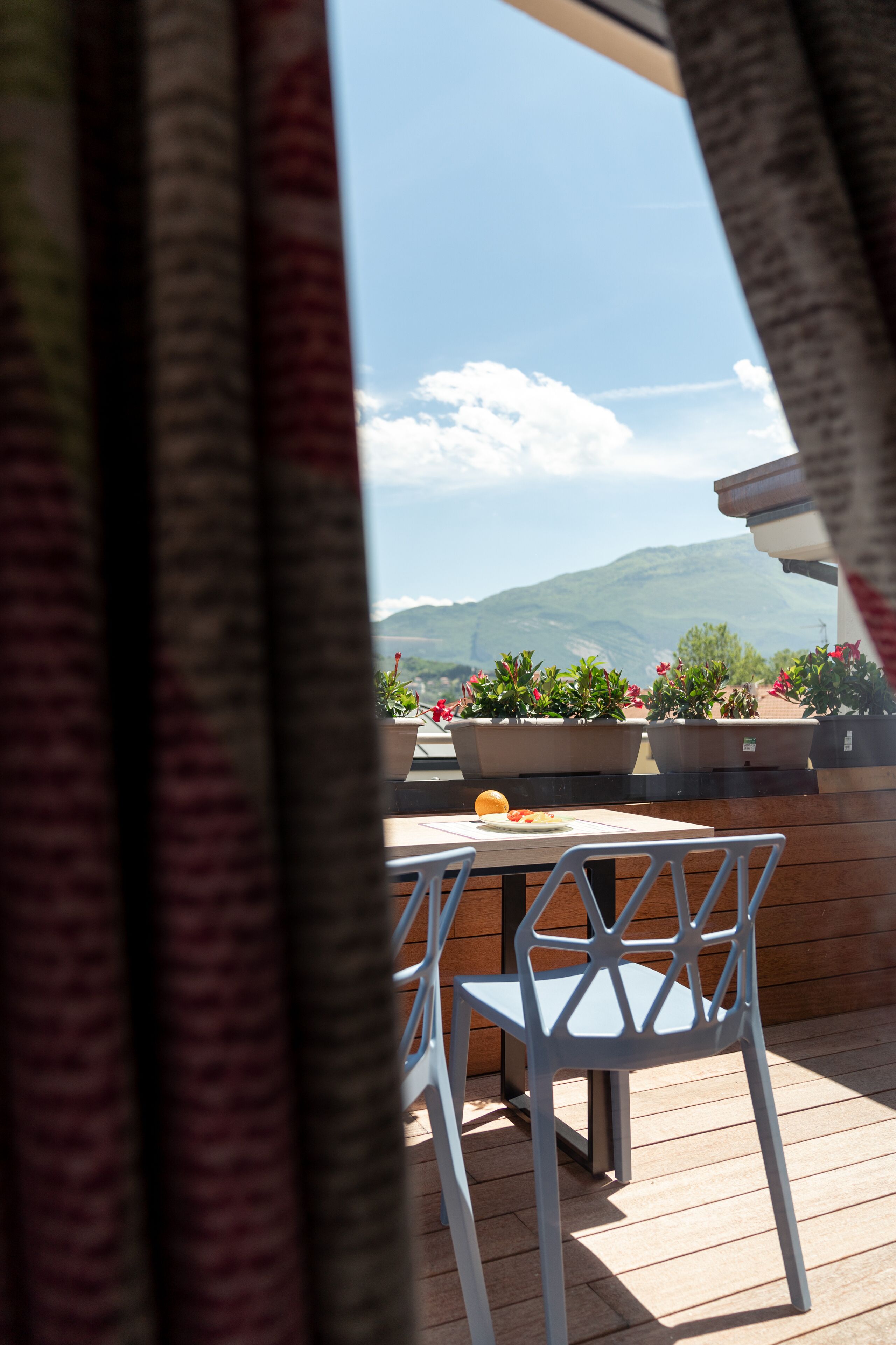 Une terrasse avec une table et des chaises, des plantes en pot et une vue sur une montagne.
