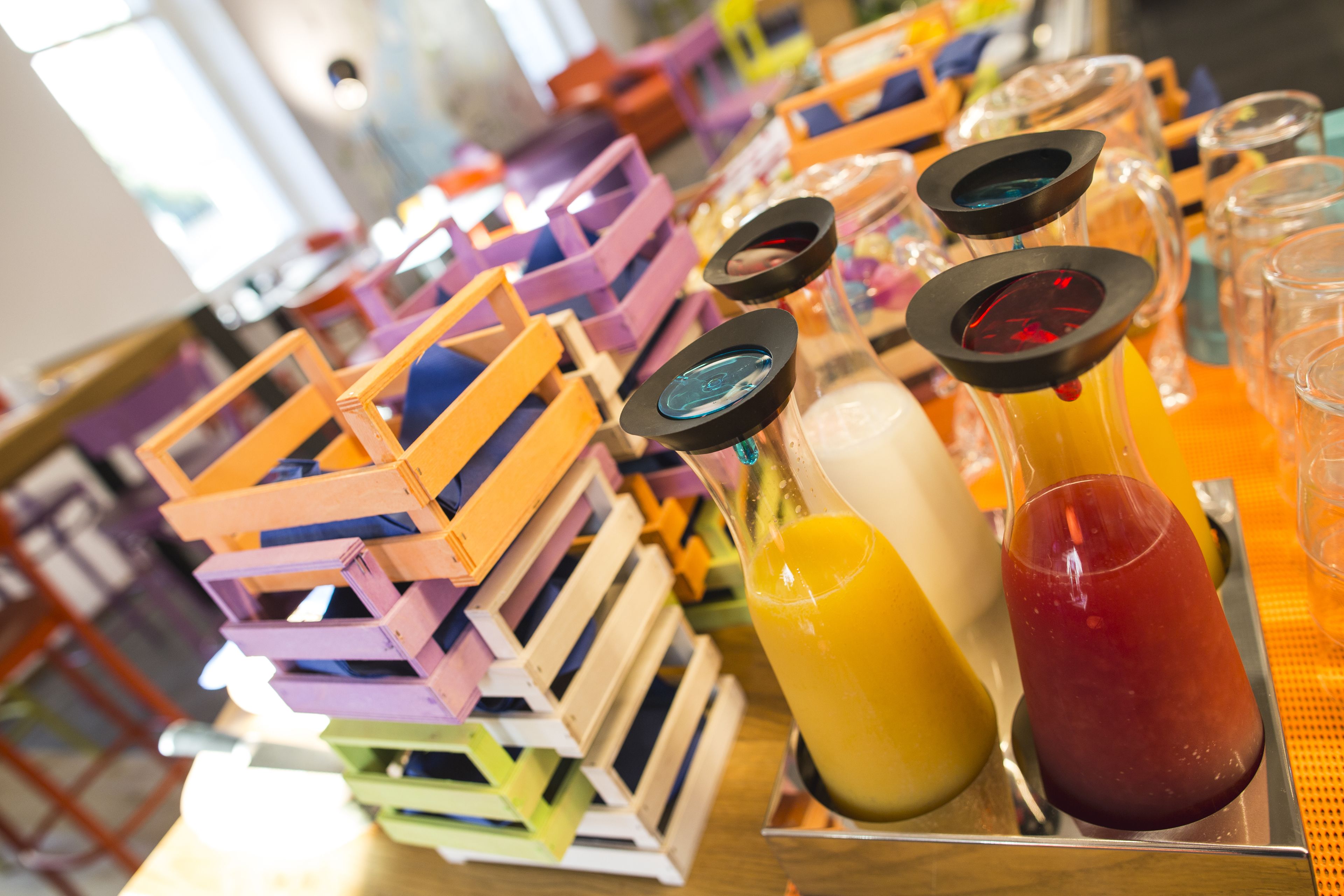 Eine Barbereich mit gestapelten Holzkisten und Gläsern mit Orangensaft und einem roten Getränk.