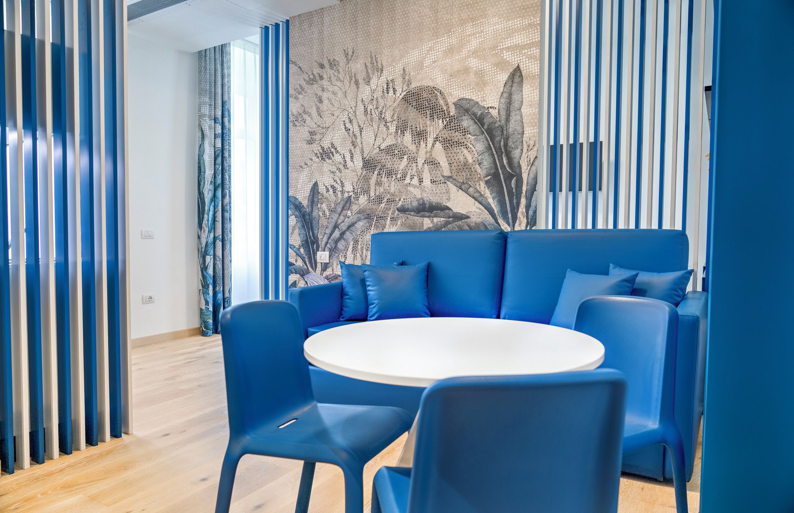 Une pièce moderne avec un canapé bleu, une table ronde et des chaises bleues.