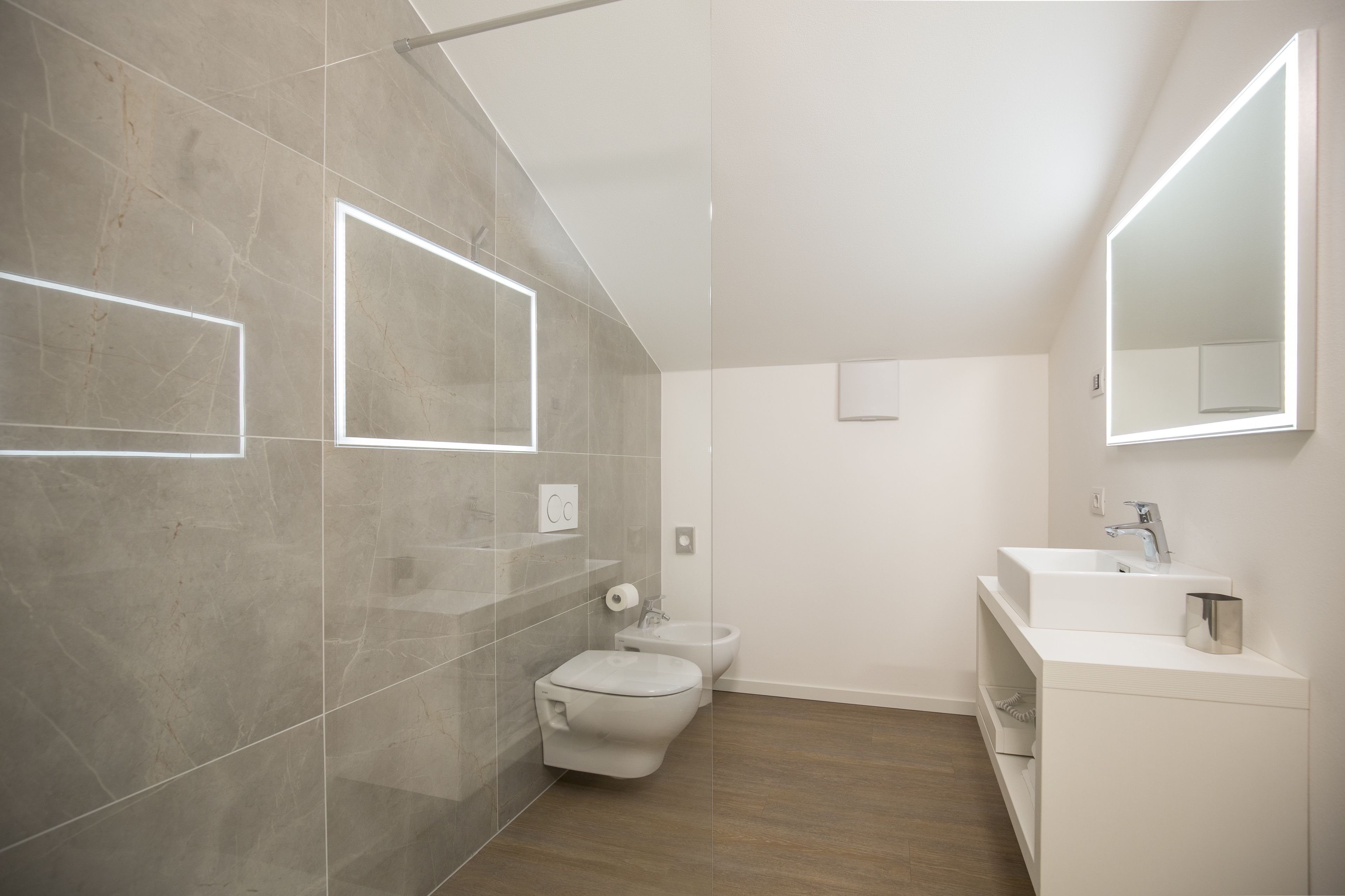 Un baño moderno con inodoro, bidé y tocador con espejo.