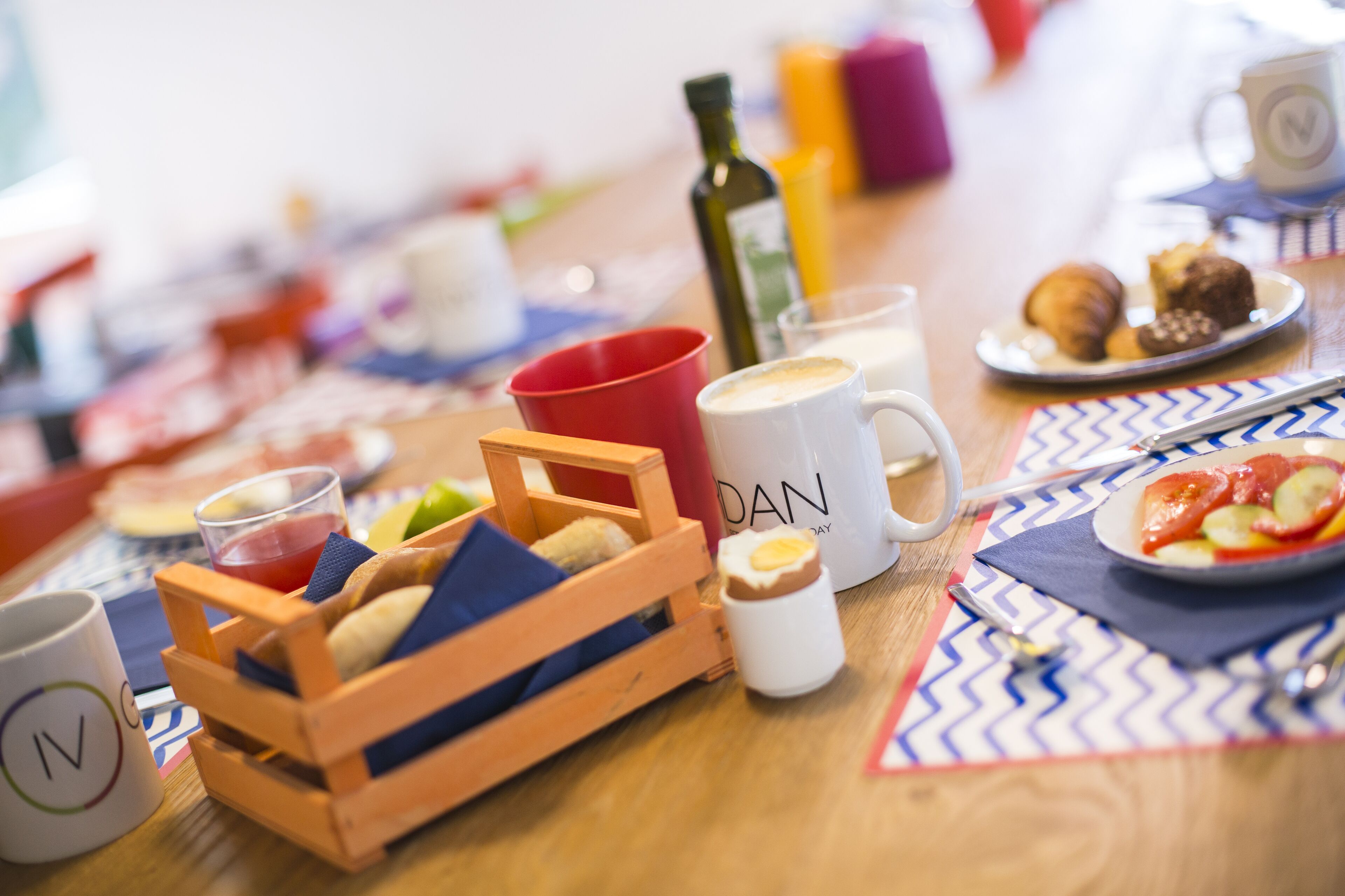 Una mesa de desayuno con diversos alimentos, una taza de café y una botella de aceite de oliva.