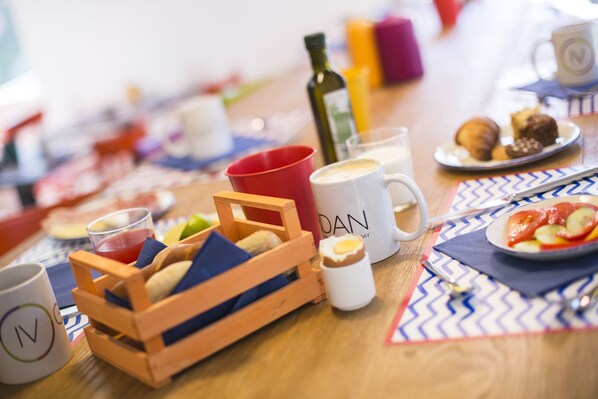 Una mesa de desayuno con diversos alimentos, una taza de café y una botella de aceite de oliva.