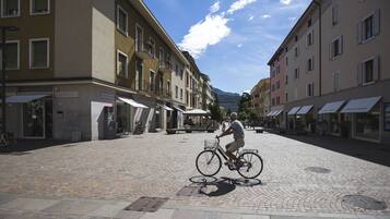 Ein Kopfsteinpflasterplatz mit Gebäuden an beiden Seiten, ein Radfahrer und ein klarer Himmel.