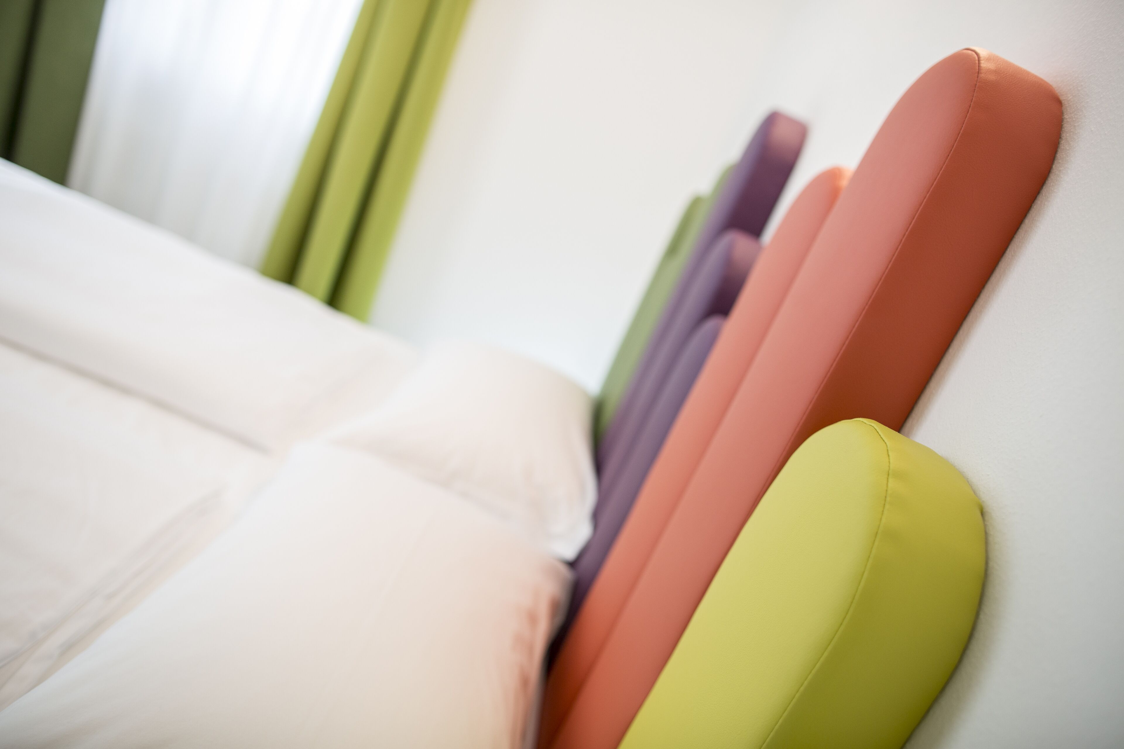 Un lit avec plusieurs oreillers de différentes couleurs.