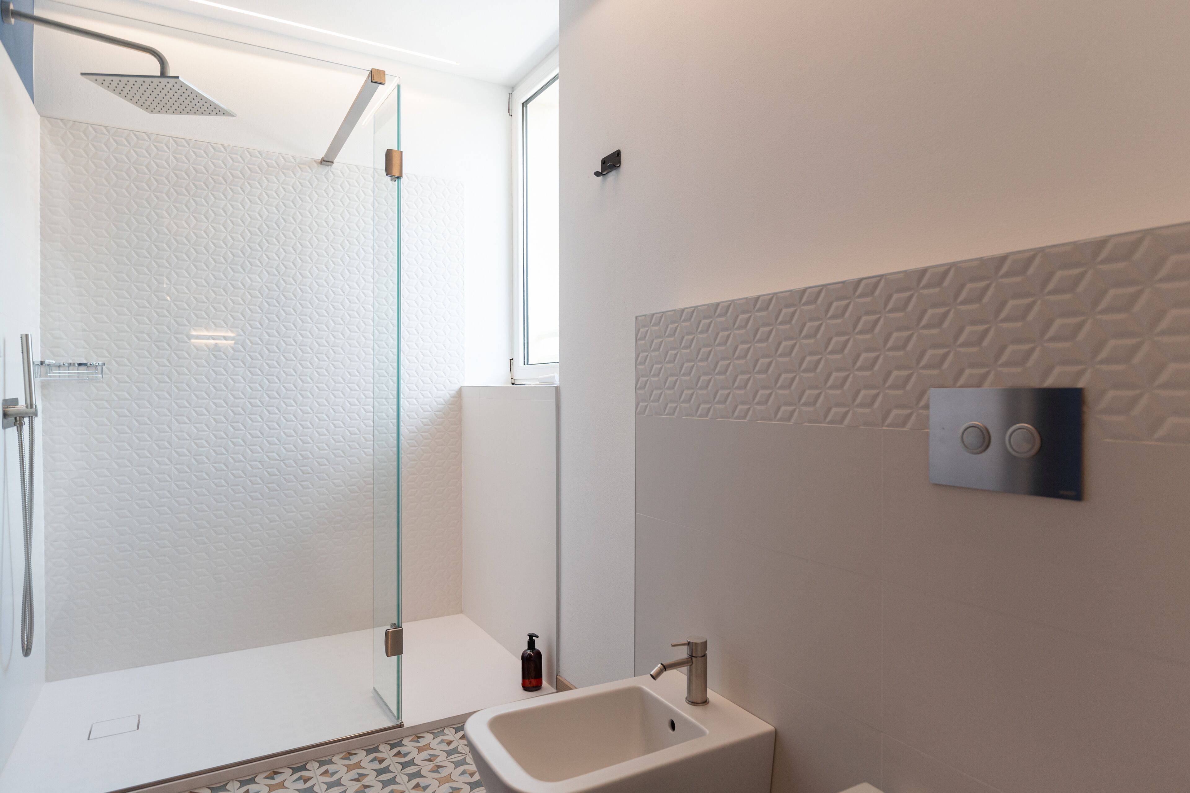 A modern bathroom with a glass shower enclosure, a white sink, and a wall-mounted control panel.