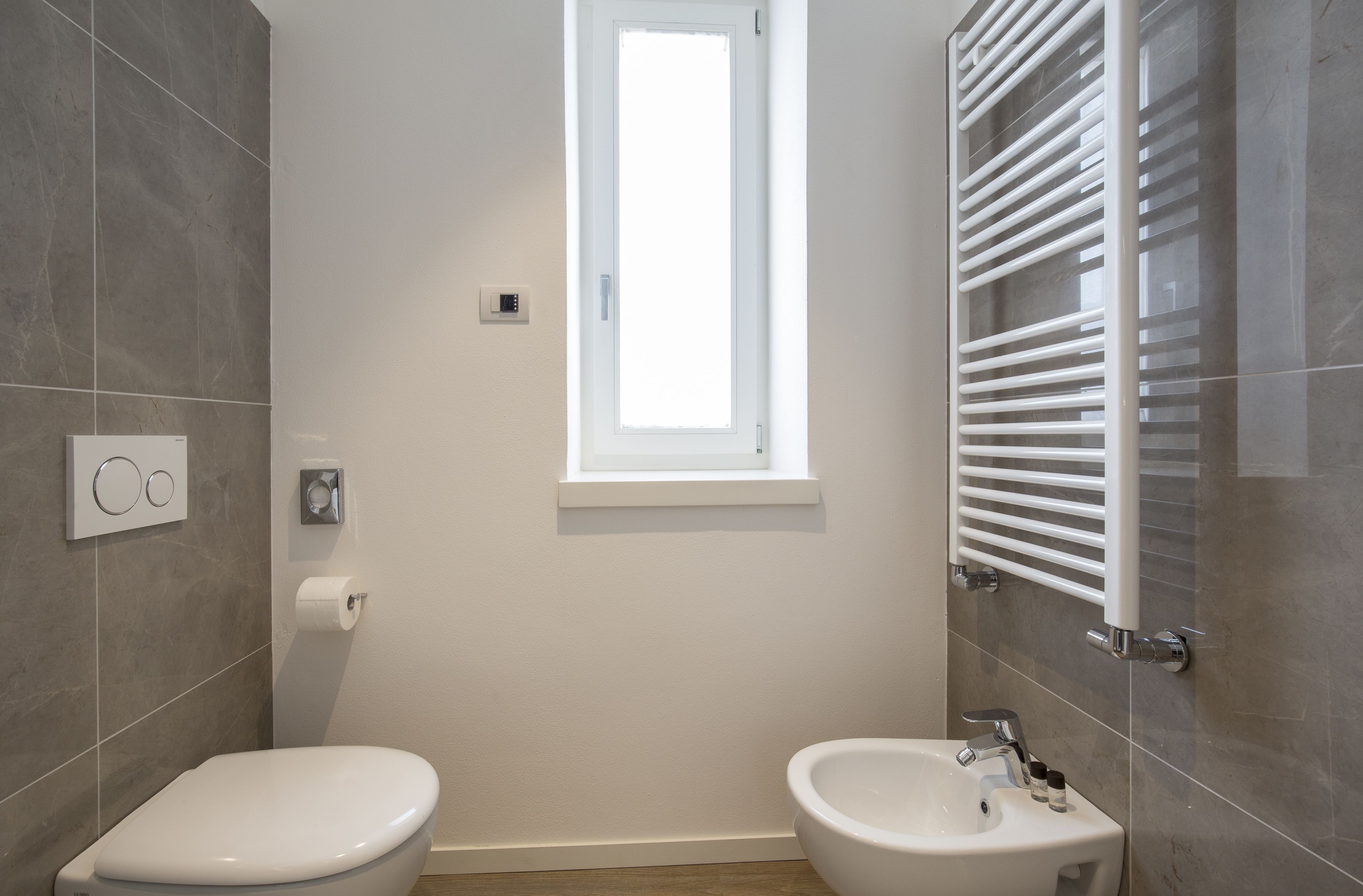 Un baño con inodoro, bidé y ventana.