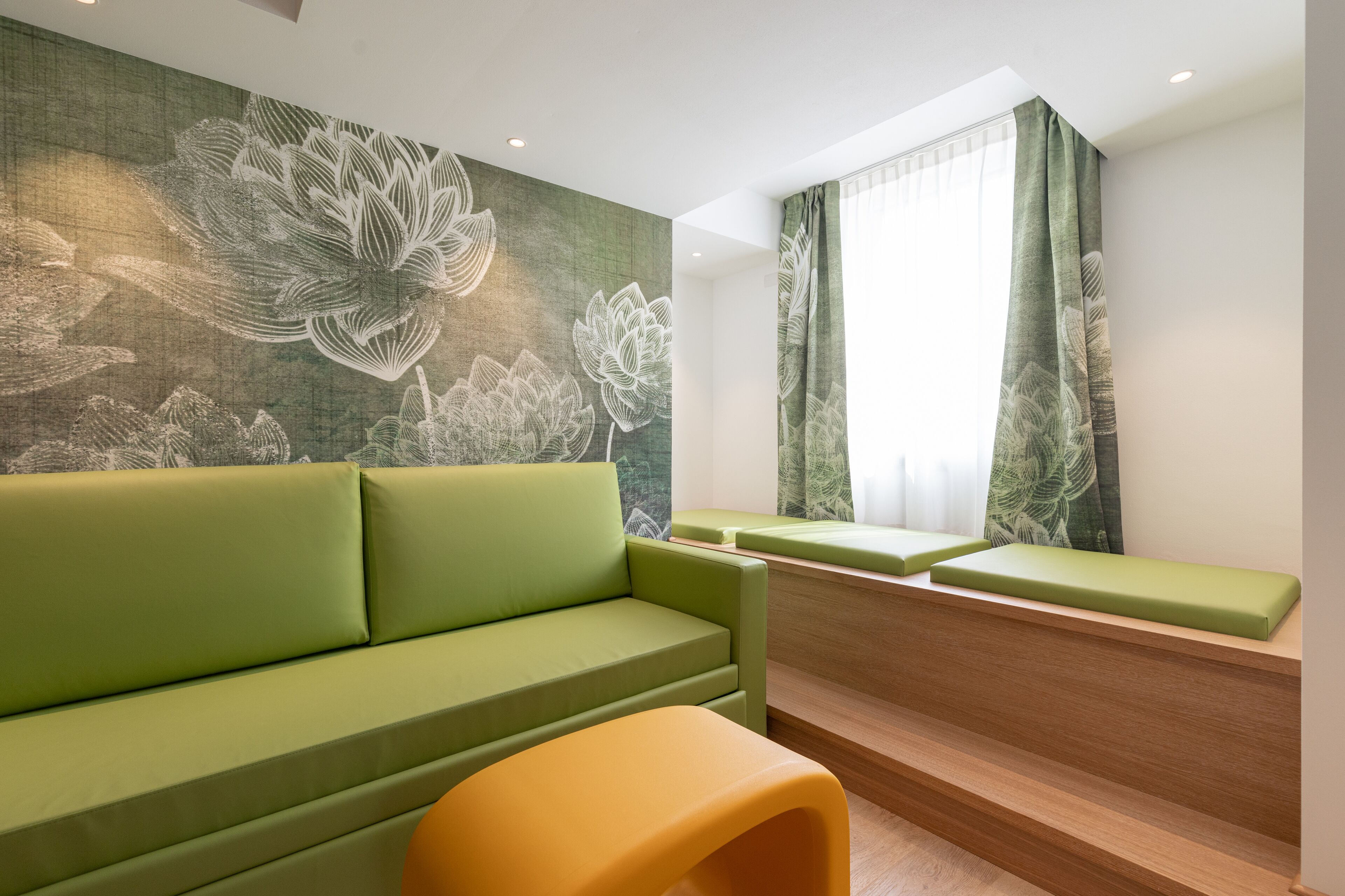 A modern room with a green sofa, a wooden bench, and a yellow chair.