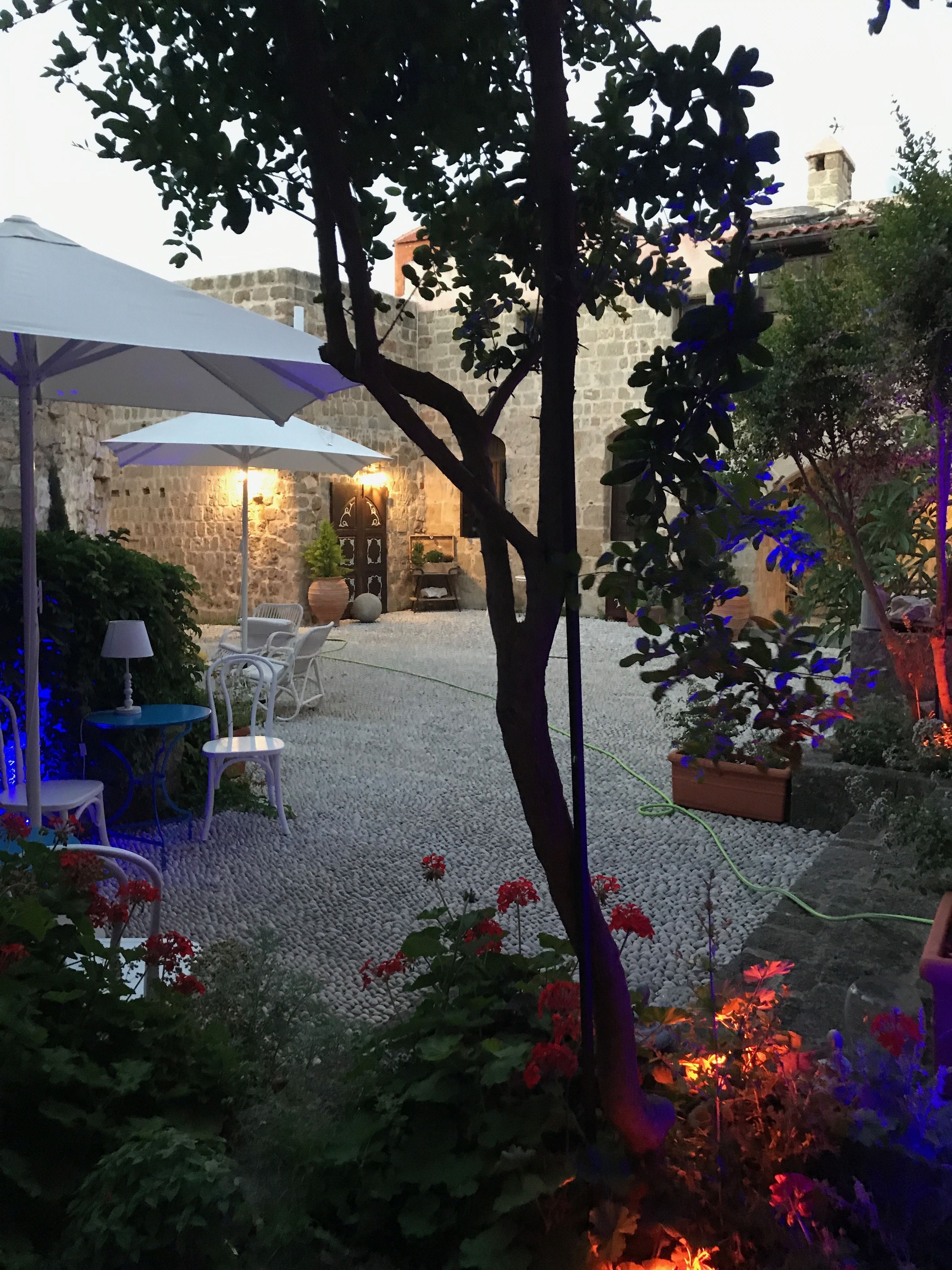 An outdoor patio area with stone walls, a table with chairs, and potted plants.