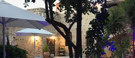 An outdoor patio area with stone walls, a table with chairs, and potted plants.