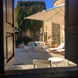 An open doorway to a patio area with outdoor furniture, a statue, and a stone wall. - Saint Artemios Hotel and Oriental Suites (Rhodes)