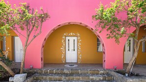 Un edificio con fachada rosa, una puerta blanca y una escalera de piedra que conduce a la entrada.