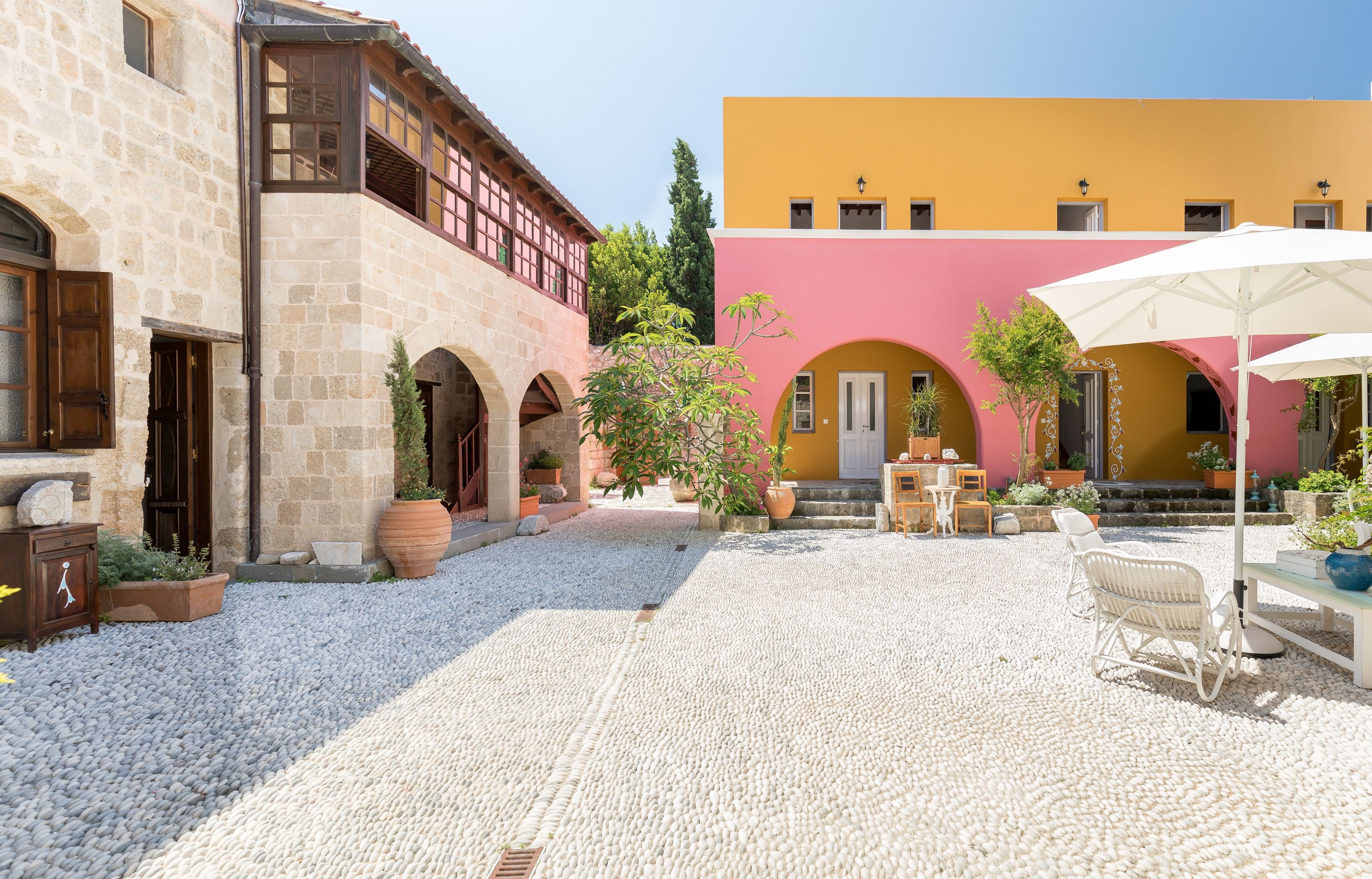 A courtyard with cobblestone flooring, outdoor seating, and potted plants.