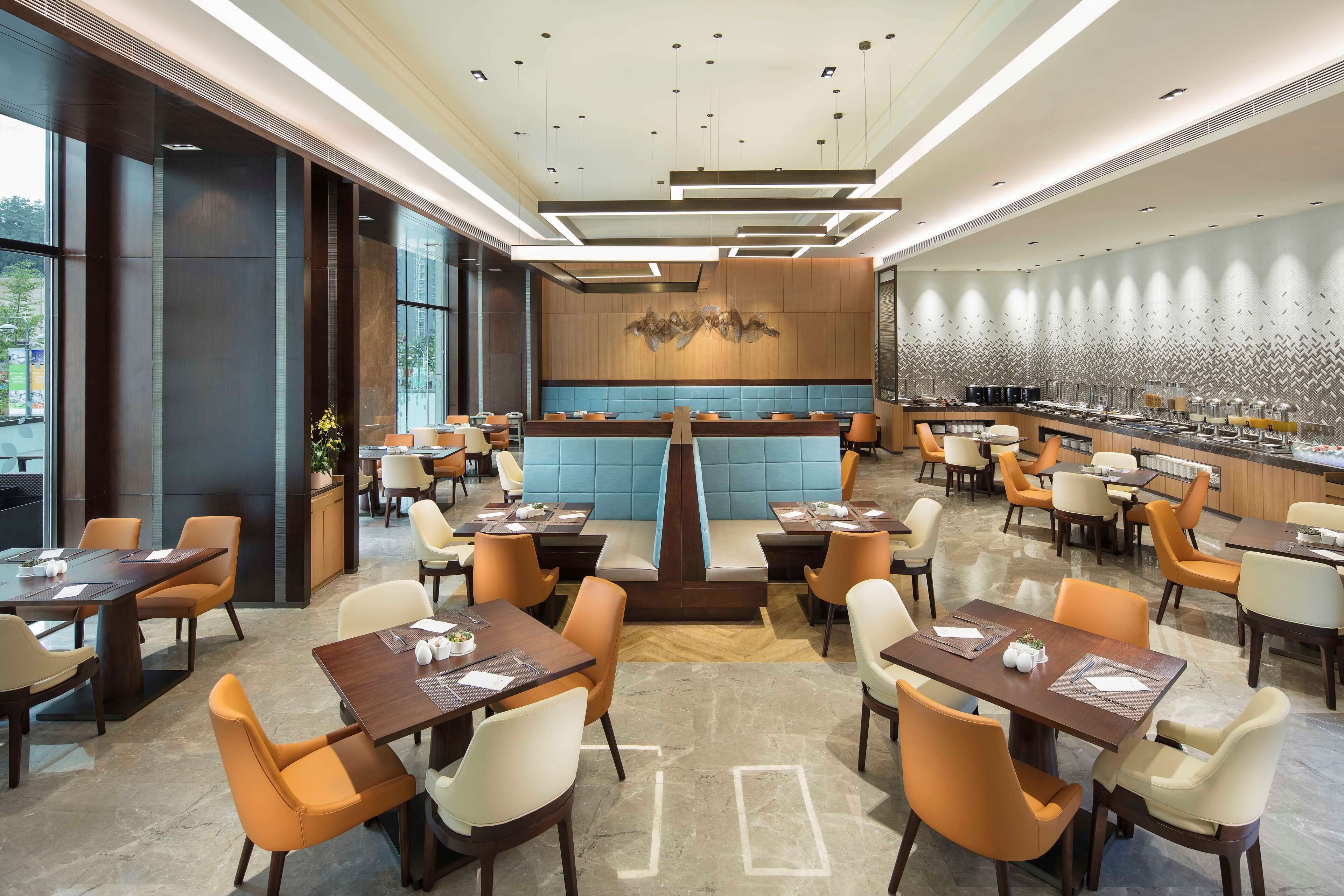 A modern restaurant with high ceilings, contemporary lighting, and a mix of seating styles including booths and tables.