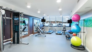 Uma academia moderna com esteiras, uma máquina de pesos e bolas de exercício.