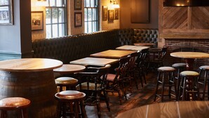 Un restaurant avec des tables et des chaises en bois, un banc rembourré et des tableaux encadrés accrochés aux murs.