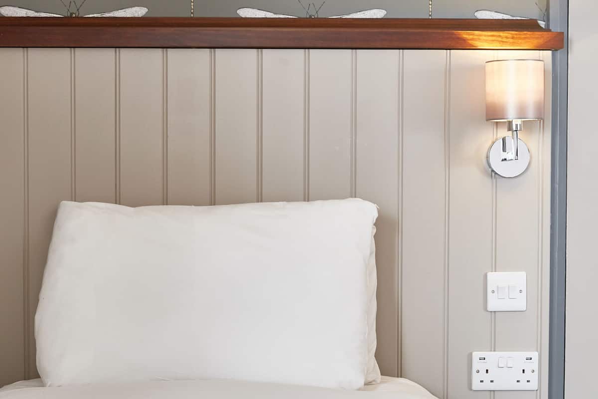 Ein Hotelzimmer mit einem Bett, einer Wandleuchte und einer Steckdose.