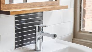 A bathroom with a white sink, chrome faucet, and a wooden-framed mirror above it.