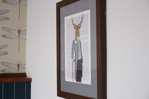 Una obra de arte enmarcada que muestra una cabeza de ciervo y una figura con traje.