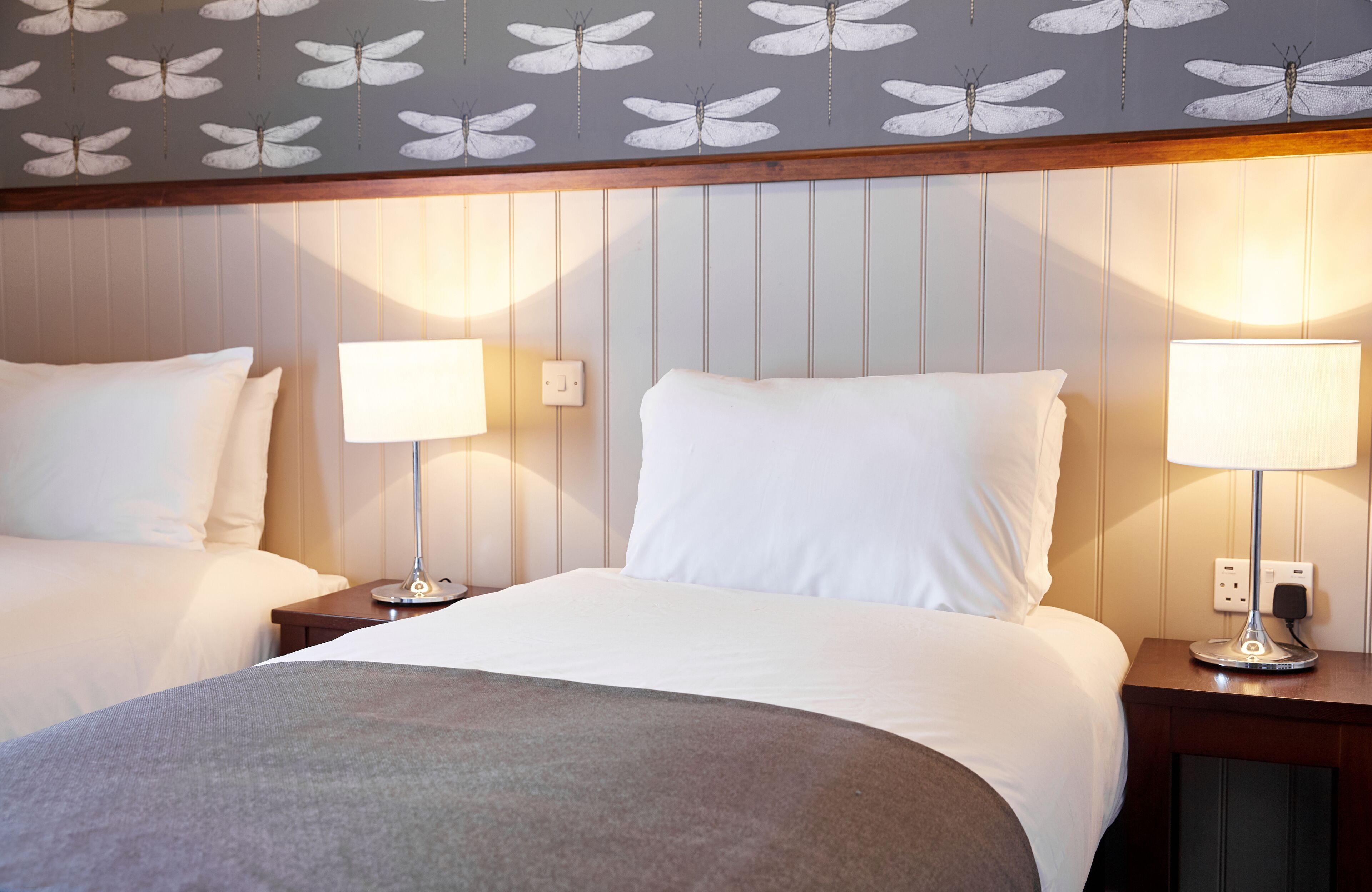 A hotel room with two beds, a patterned ceiling, and bedside lamps.