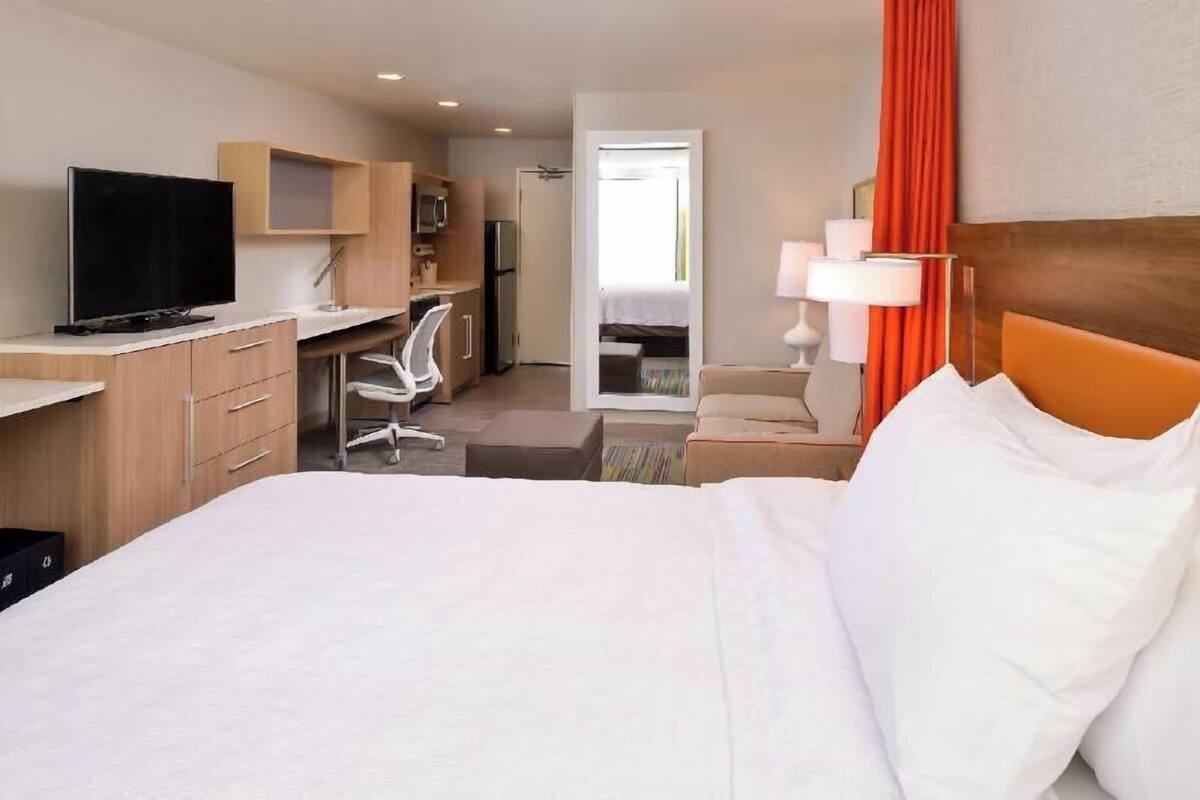 Hotelkamer met een bed, bureau, stoel, televisie en uitzicht.