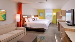 A hotel room with a sofa, two beds, a TV, and a desk. - Home2 Suites by Hilton Merrillville (Merrillville)