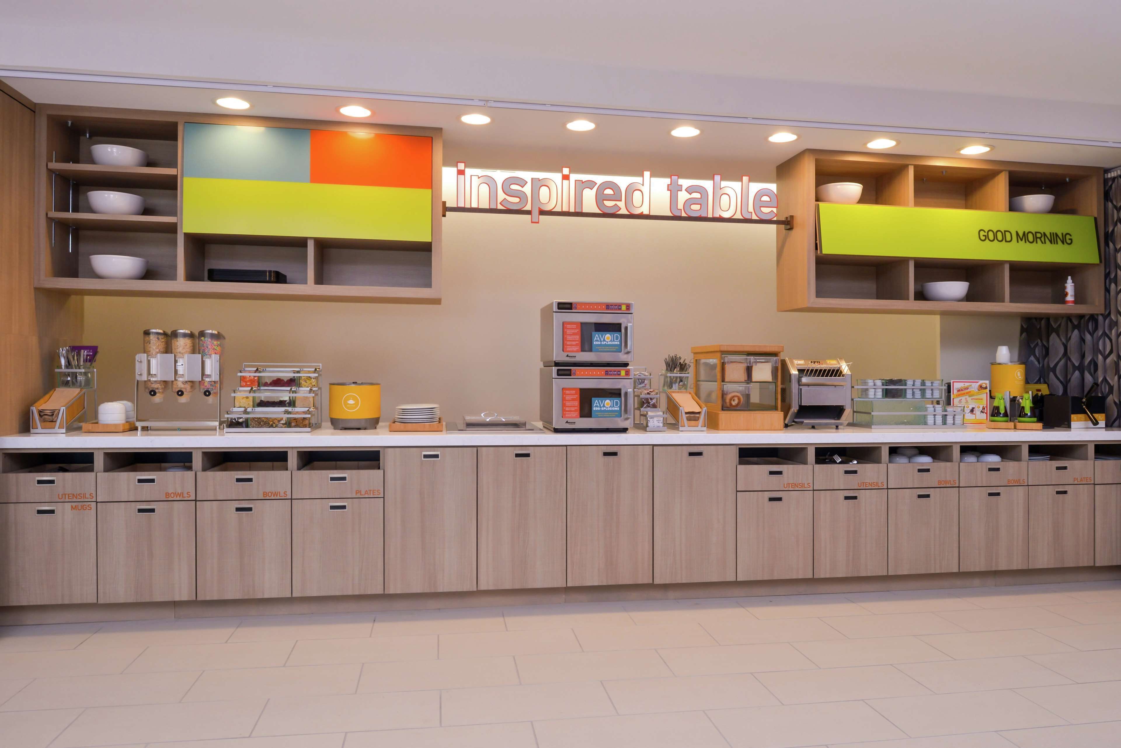 A modern kitchen area with a sign reading "inspired table" and a "GOOD MORNING" sign.