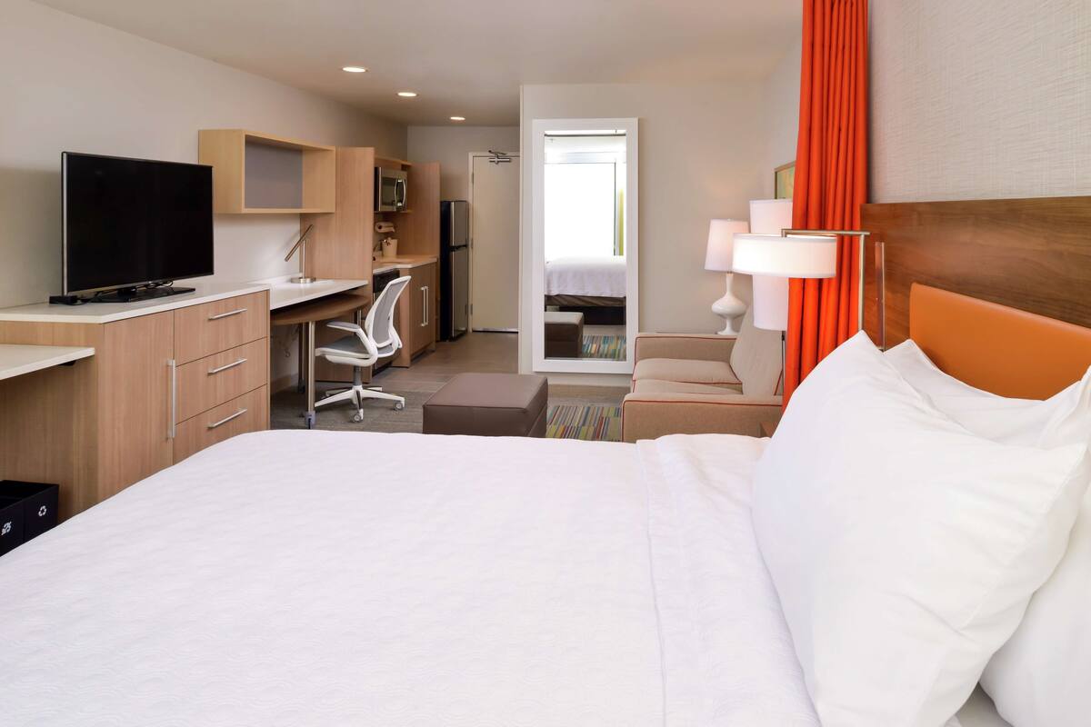 Hotelkamer met bed, bureau, stoel, televisie en uitzicht.