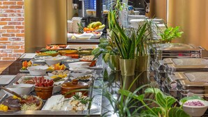A buffet table with various food items and a coffee machine in the background. - INX Design Hotel (Kraków)