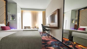 Una habitación de hotel con una cama grande, un escritorio, una silla, un espejo y una ventana con cortinas.