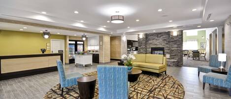 A spacious lobby with a reception desk, seating area, and a stone fireplace.
