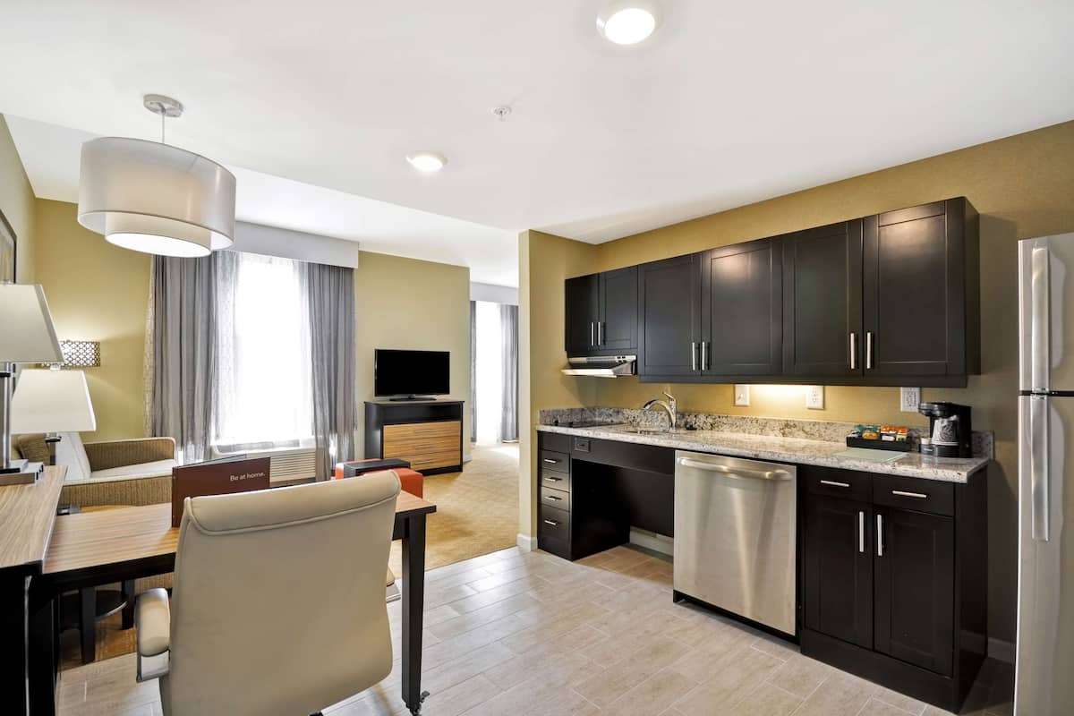 A modern kitchen with dark cabinets, stainless steel appliances, and a dining area with a table and chairs.