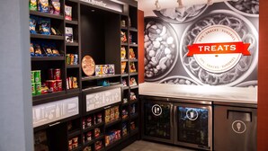 A snack display area with various packaged treats and a vending machine. - Hampton Inn Pontiac (Pontiac)