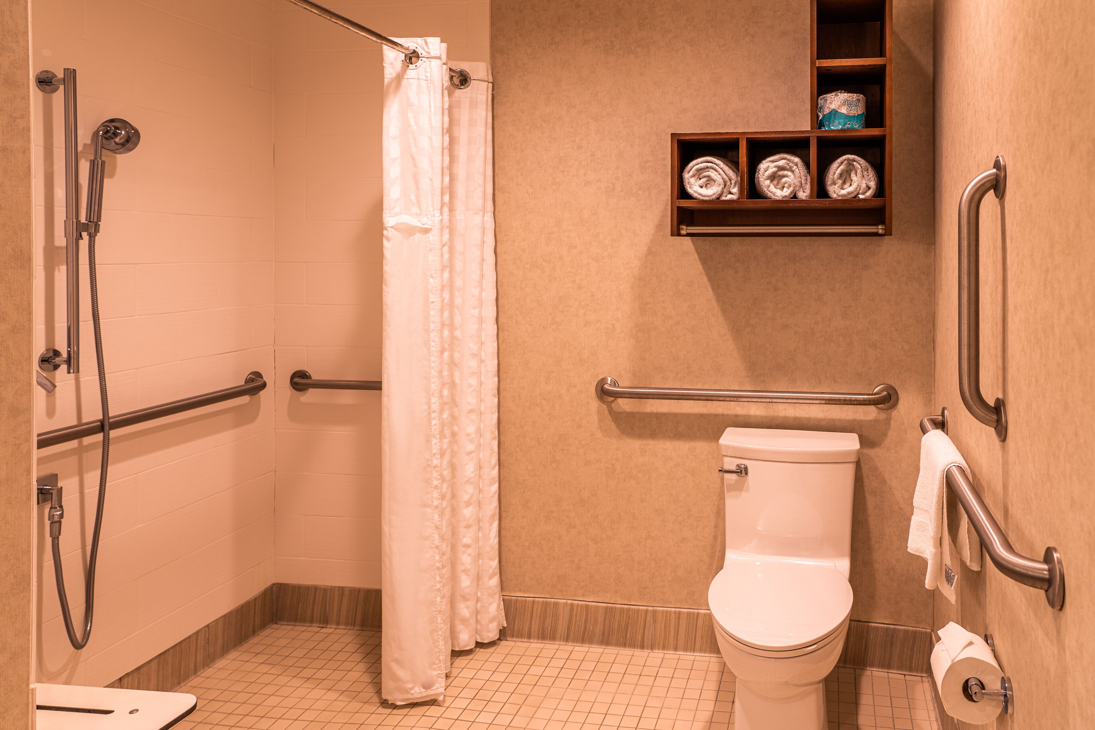 A bathroom with a shower, toilet, and a shelf with towels.