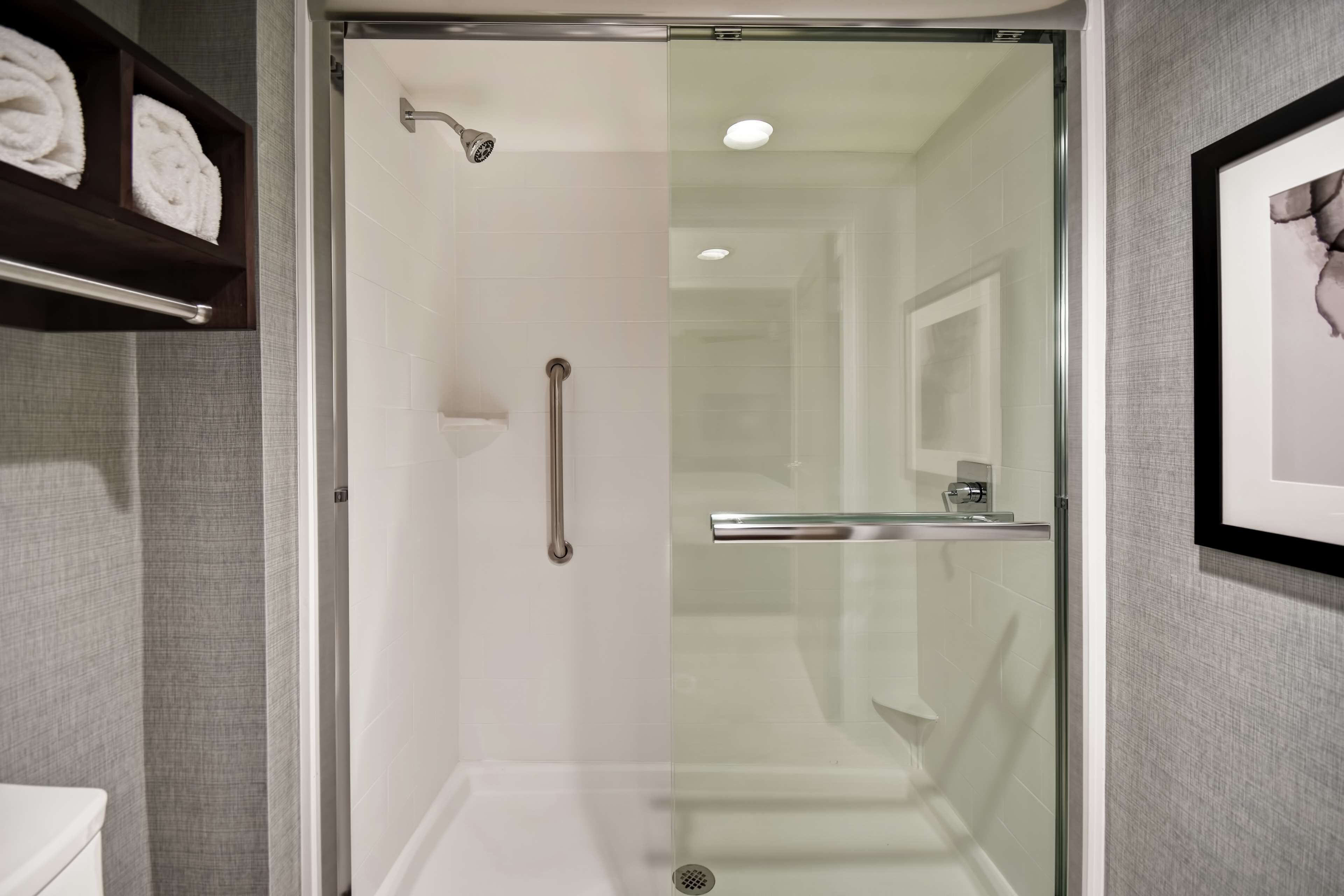 A modern bathroom with a glass-enclosed shower, a white toilet, and a towel rack.