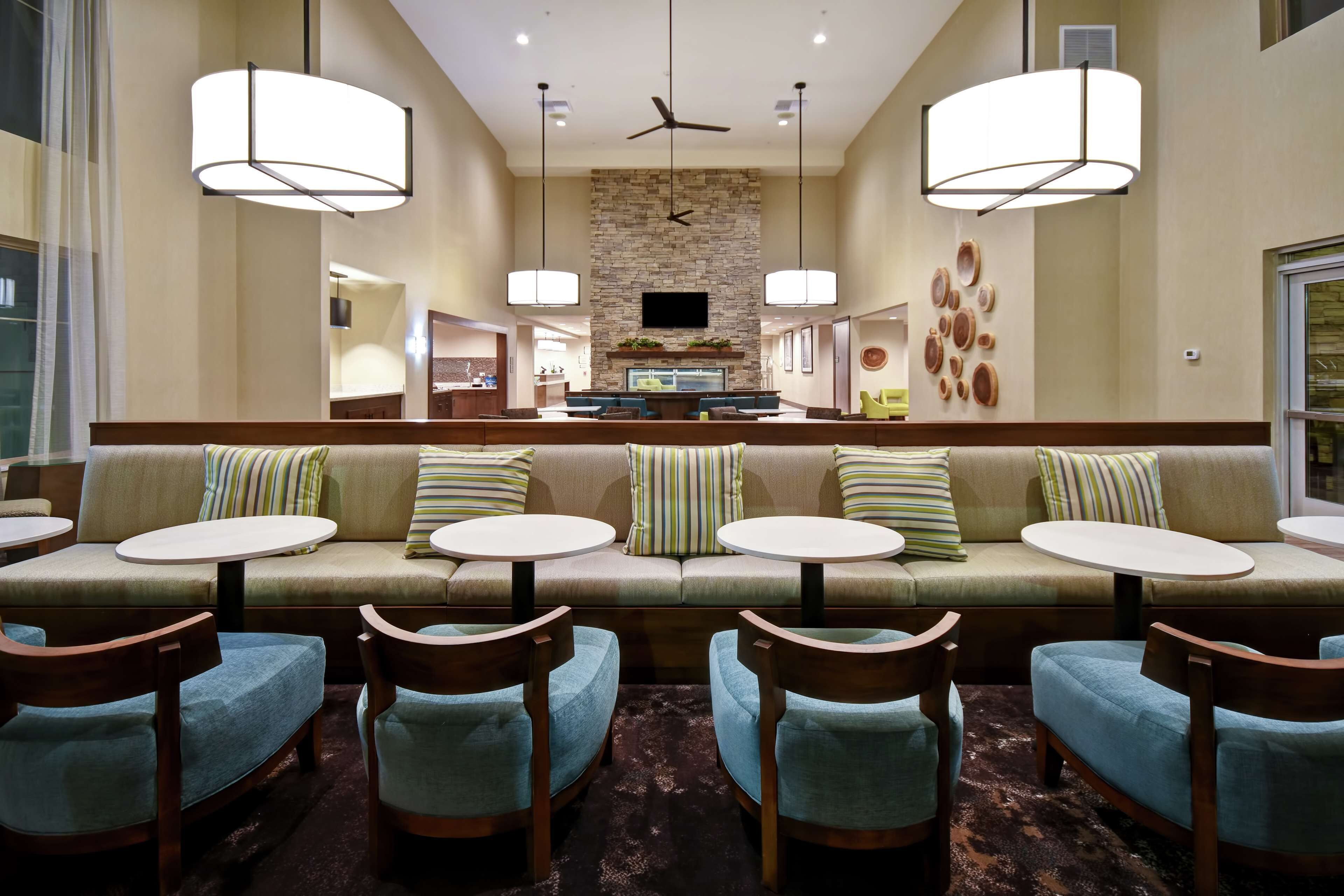 A hotel lobby with a central seating area, a stone wall, a flat-screen TV, and a ceiling fan.