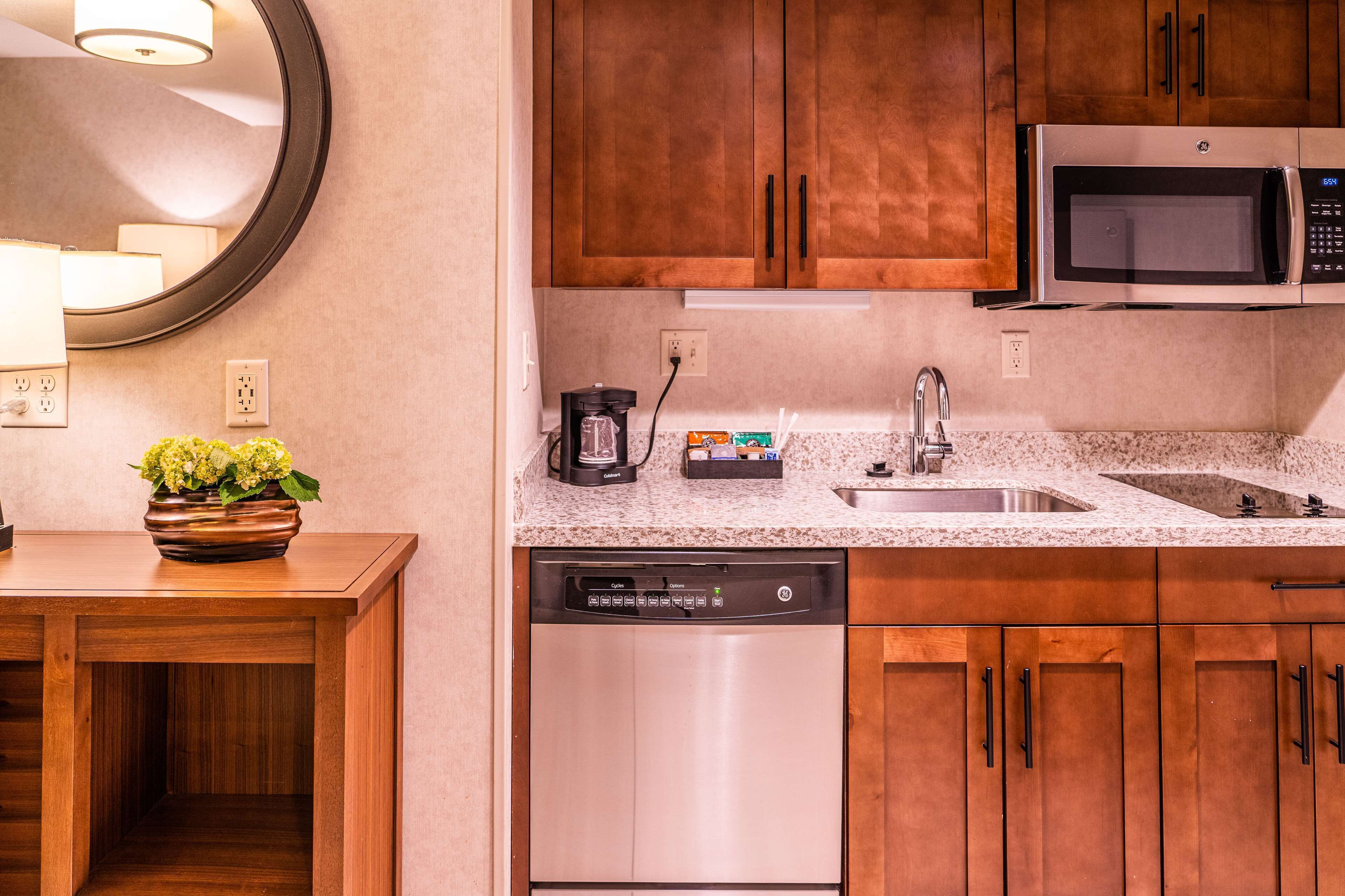 A kitchen with wooden cabinets, a stainless steel dishwasher, a microwave, and a coffee maker.