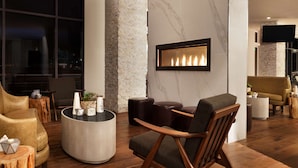 Una sala de estar moderna con chimenea, asientos cómodos y un ventanal grande.