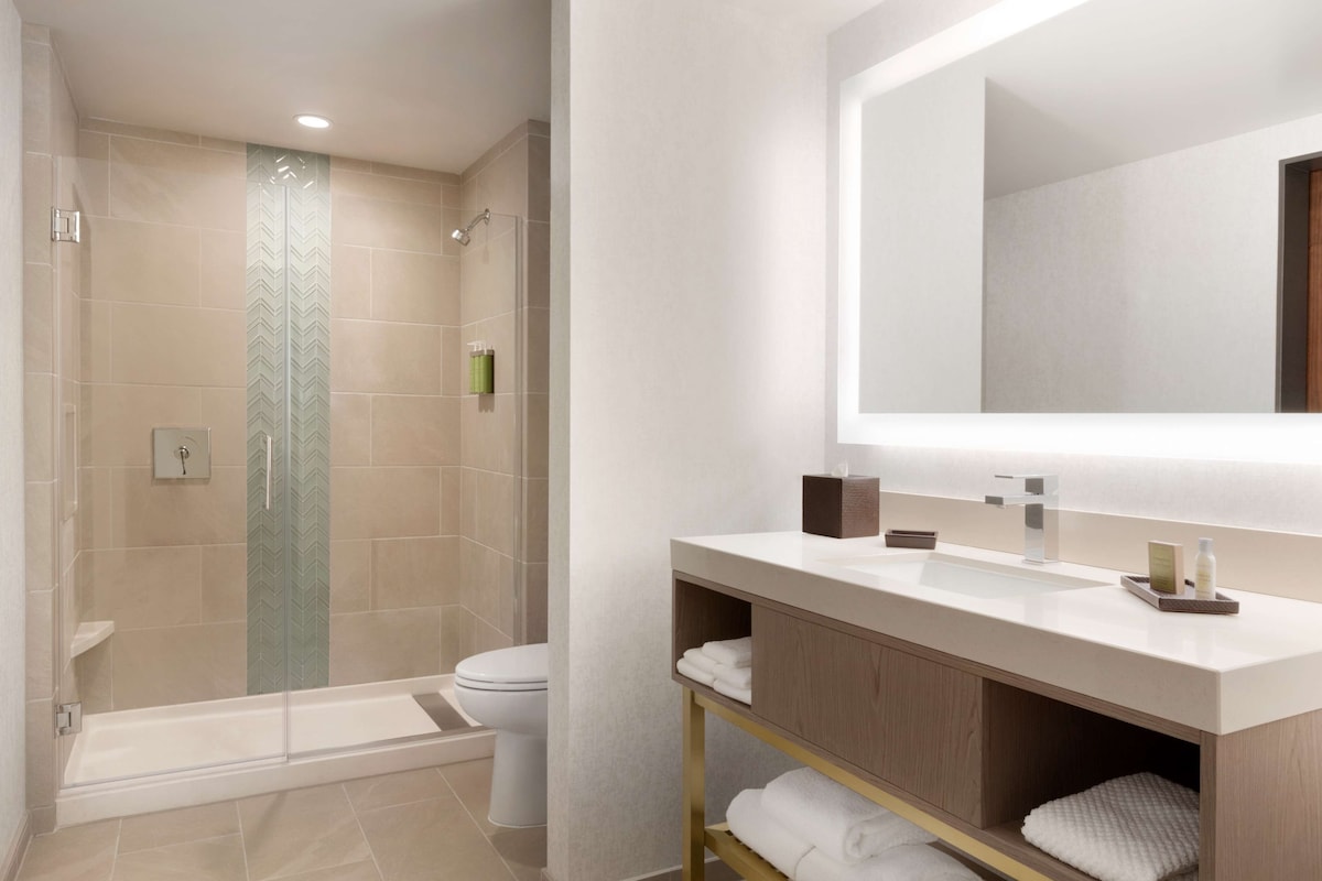 Un baño moderno con cabina de ducha de vidrio, inodoro y tocador con espejo.