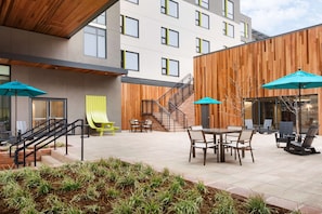 An outdoor patio area with a wooden deck, outdoor seating, and a staircase leading to an upper level.