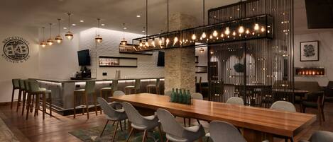 Cocina y comedor modernos con una larga mesa de madera, sillas grises e iluminación colgante.