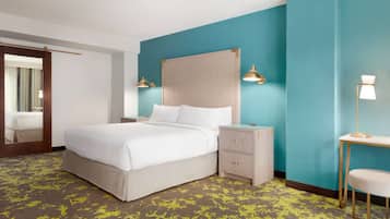 Una habitación de hotel con cama, mesitas de noche, un espejo y una mesilla.