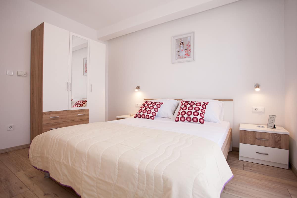 A bedroom with a large bed, a wardrobe, bedside tables, and a wall-mounted light fixture.